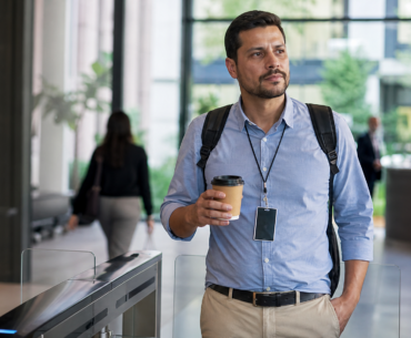 Profissional com crachá e café no escritório representando coffee badging no trabalho híbrido