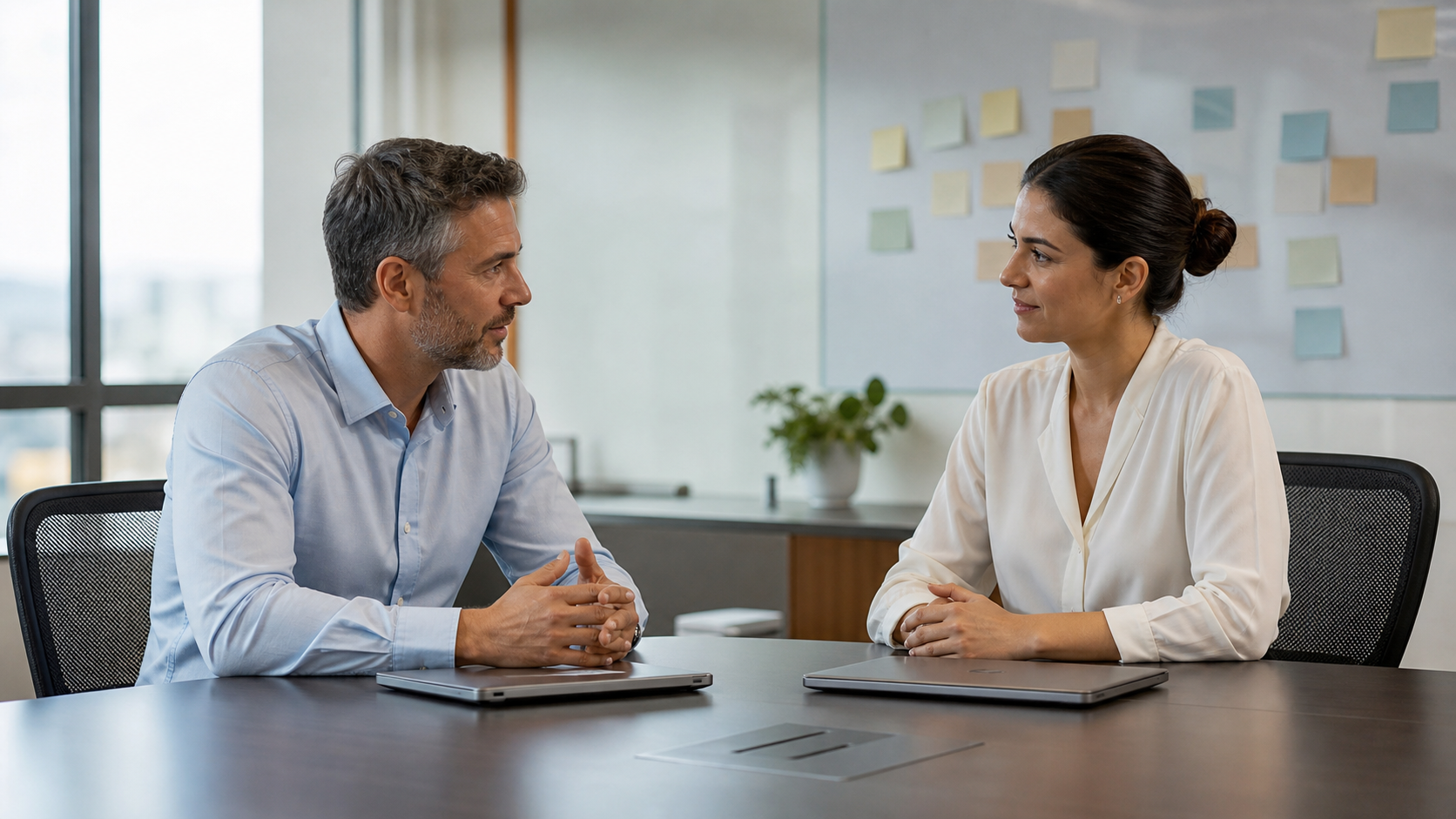 Eficácia dos gestores: como o RH mede liderança Gestor conversa com profissional em sala de reunião sobre prioridades e desenvolvimento da equipe