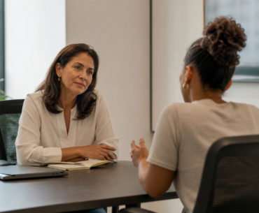 Líder escutando pessoa da equipe com expressão de cuidado e cansaço em ambiente corporativo