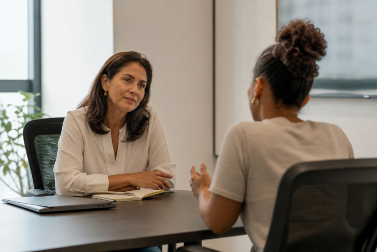 Líder escutando pessoa da equipe com expressão de cuidado e cansaço em ambiente corporativo