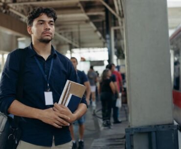 Jovem que trabalha e estuda leva cadernos e bolsa em uma estação de trem